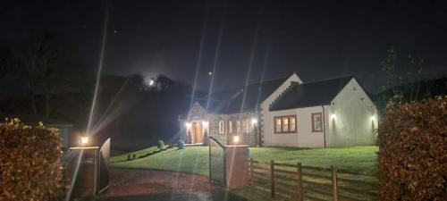 ein Haus in der Nacht mit Lichtern davor in der Unterkunft Auchendennan Farm Self Catering Cottages in Balloch