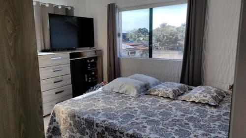 een slaapkamer met een bed, een tv en een raam bij Casa Da Ana in Caraguatatuba