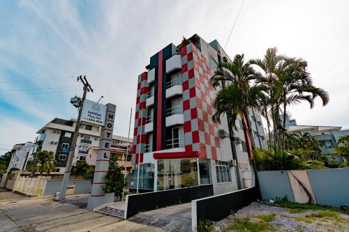 un edificio alto con palmeras delante en HANNA Praia Hotel - Florianópolis, en Florianópolis
