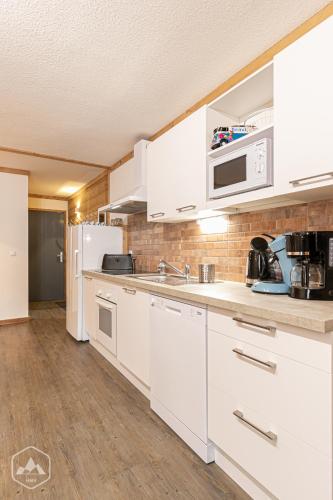 une cuisine avec des armoires blanches et des appareils électroménagers blancs dans l'établissement Côté-Bourget 6 pers LA POINTE DE LONGECOTE, proche La Norma et Aussois, à Villarodin-Bourget