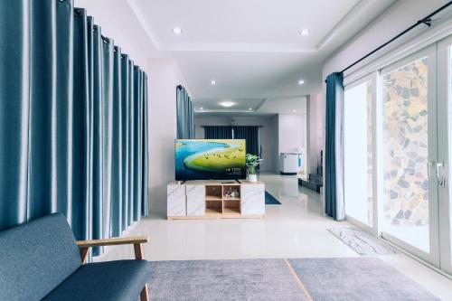 a living room with blue curtains and a painting on the wall at AABAN House 03 in Hat Yai