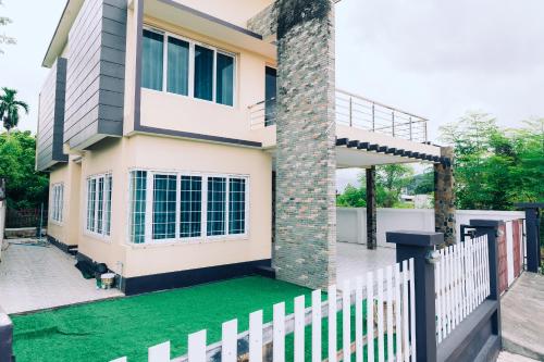 une maison avec une clôture blanche et une pelouse verte dans l'établissement AABAN House 03, à Hat Yai