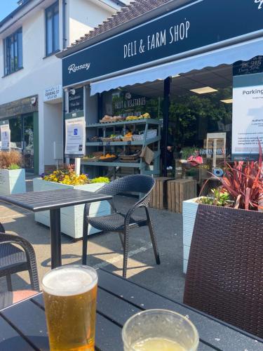 a glass of beer sitting on a table in front of a store at Ocean Cottage, Ferring - seaside cottage moments from the beach and Bluebird cafe in Ferring