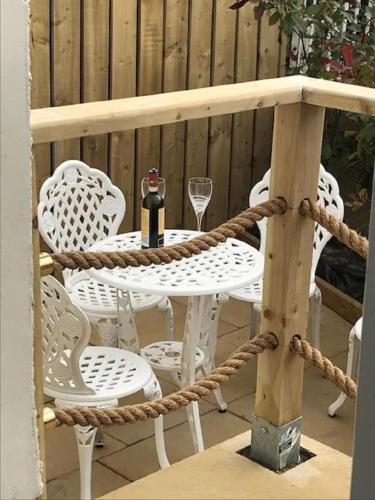 a table with a bottle of wine and chairs on a patio at Rathlin Sound Apartment, Ballycastle in Ballycastle