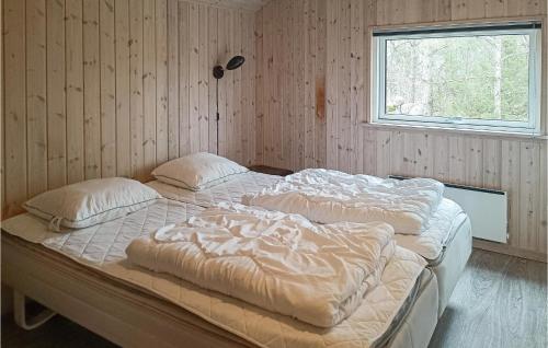 a bedroom with two beds with pillows and a window at Nice Home In Kpingsvik With Sauna in Grönskog