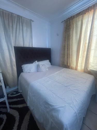 a bedroom with a bed with white sheets and windows at Maimoon homes in Malindi