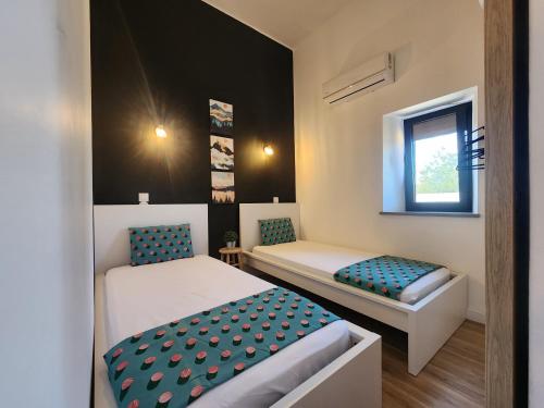 a small room with two beds and a window at Luz Do Sul Holiday Rental - Pedras in Moncarapacho