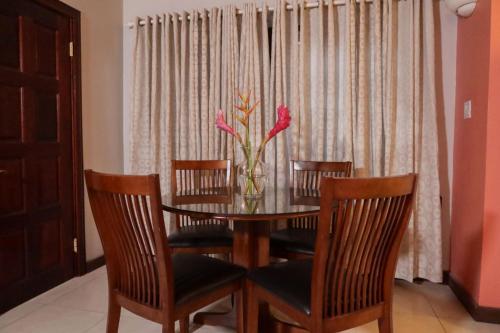 ein Esstisch mit Stühlen und einer Vase mit Blumen darauf in der Unterkunft Trilogy Villas in English Harbour Town