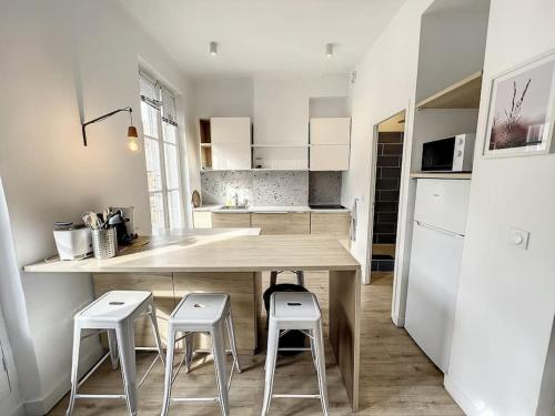 une cuisine avec une table en bois et deux tabourets dans l'établissement PLACE - Appartement lumineux au coeur de la Joliette, à Marseille