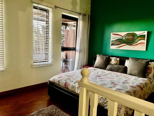 a bedroom with a bed and a green wall at Weaver Place in Bloubergstrand