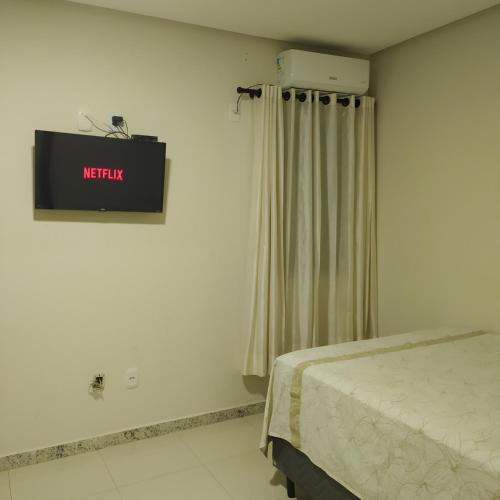 a room with a bed and a television on the wall at HOTEL DALU Caetité Ba in Caetité