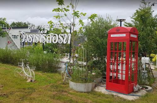 eine rote Telefonzelle in einem Garten mit einem Schild in der Unterkunft วิวธารารีสอร์ท (ViewThara Resort) in Ban Chak Phak Kut