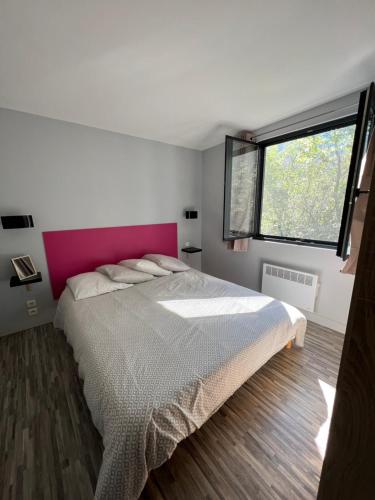a bedroom with a large bed with a pink headboard at Gîte La Cerise Qui Rit in La Cresse