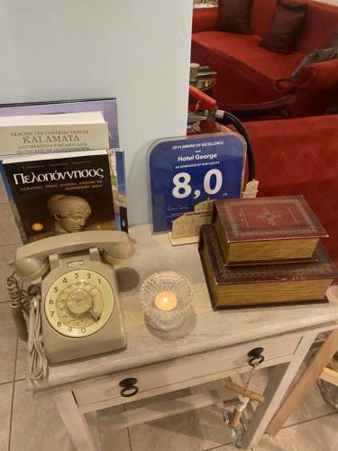 a table with a clock and books on it at Hotel George in Kalamata