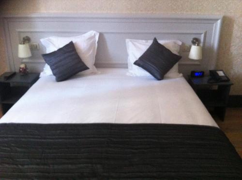 a bedroom with a large white bed with pillows at Hotel Restaurant Edmond's in Cap d'Ail