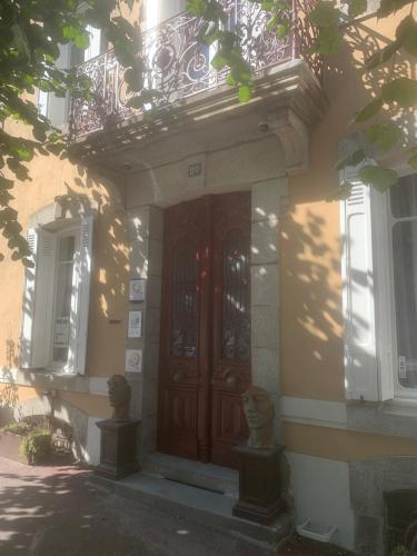 Cette maison dispose d'une porte en bois et d'un balcon. dans l'établissement GUESTHOUSE La VILLAE, à Mazamet