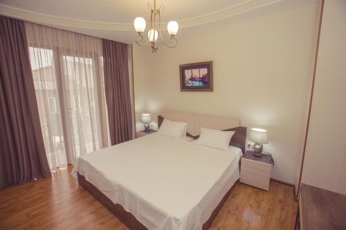 a bedroom with a large white bed and a chandelier at Royal Venezia Hotel in Batumi