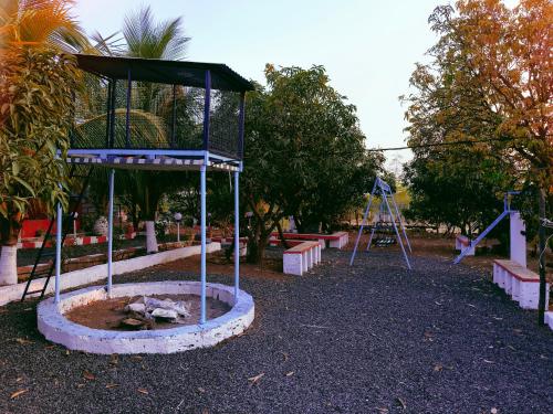 un parque con columpios y parque infantil en Madhav Farmhouse en Sasan Gir