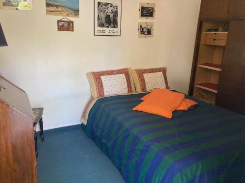 een slaapkamer met een bed met een oranje kussen erop bij Habitación con baño privado, barbacoa y entrada independiente en carrasco in Montevideo