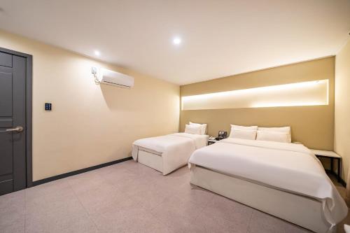 a hotel room with two beds and a door at Hotel Rodem in Incheon