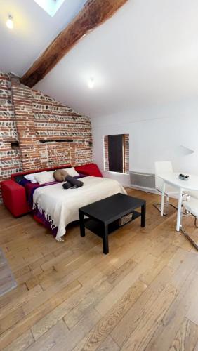 - une chambre avec un lit et un mur en briques dans l'établissement Appartement de charme Toulouse nord, à Aucamville