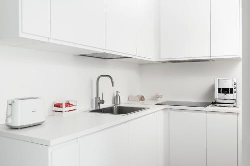 una cucina bianca con mobili bianchi e un lavello di MOH - Casa Vacanze a Grottaglie