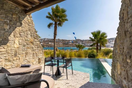 a patio with a table and chairs next to a pool at Aeonic Suites and Spa in Mýkonos City