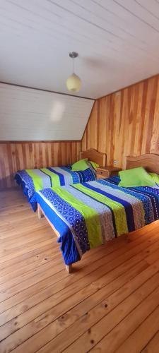 two beds in a room with wooden floors at cabaña in Pucón