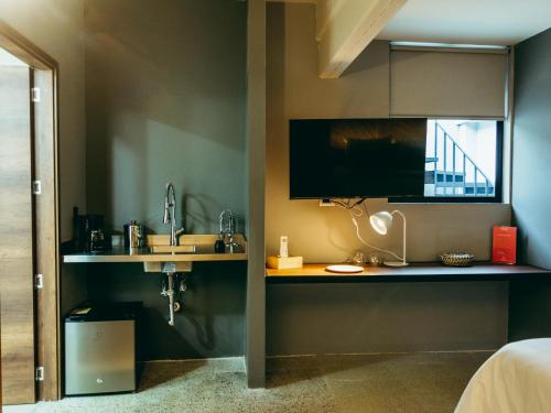 a bedroom with a sink and a tv on a wall at I Believe- All Suite Manila-Poblado in Medellín