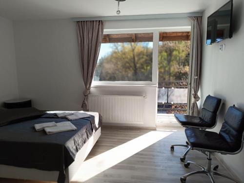 een slaapkamer met een bed en 2 stoelen en een raam bij VIV Rosetti in Iaşi