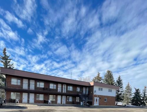 a brick building with a cloudy sky in the background at Rest Easy Motel in Three Hills