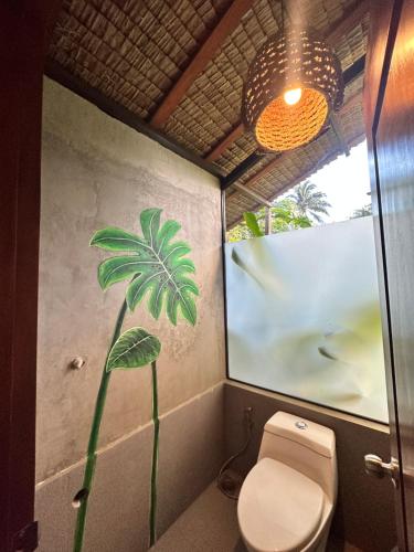 a bathroom with a toilet and a painting on the wall at Nay Morena Villa 