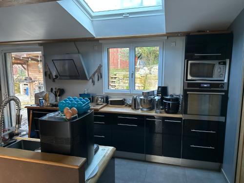 une cuisine avec des armoires noires et une fenêtre dans l'établissement Maison de charme avec gîte équestre, à Retheuil