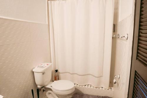 a bathroom with a toilet and a shower curtain at Art Inspired Apt Besides Governors Mansion in OSJ - Fort Apt 11 in San Juan