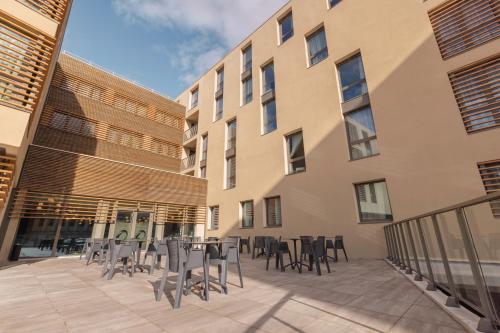 a patio with tables and chairs in front of a building at The Originals Résidence Aix Schuman in Aix-en-Provence