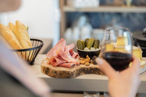 a person holding a glass of wine and a plate of food at The Originals Résidence Aix Schuman in Aix-en-Provence