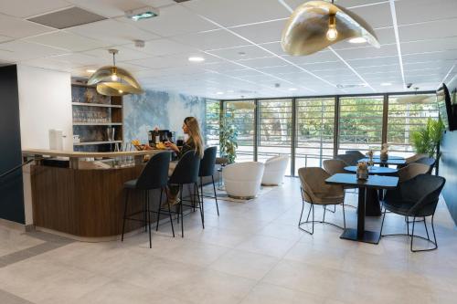 a woman sitting at a counter in a restaurant at The Originals Résidence Aix Schuman in Aix-en-Provence