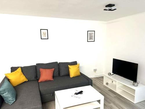 sala de estar con sofá gris y almohadas coloridas en Stylish Apartment At Carlton Grove, en Londres