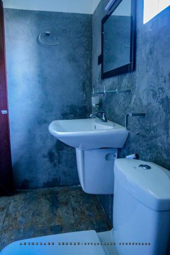La salle de bains est pourvue d'un lavabo blanc et de toilettes. dans l'établissement The Anchorage Resort, à Polonnâruvâ