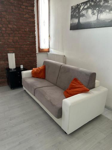 ein weißes Sofa mit zwei orangefarbenen Kissen im Wohnzimmer in der Unterkunft Milano Via Ripamonti IEO in Mailand