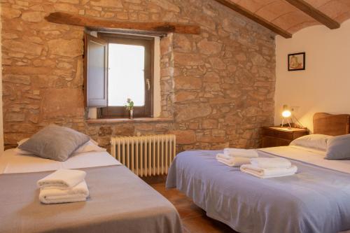 two beds in a room with a stone wall at Mas Cal Gira in Moià