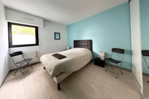 um quarto com uma cama com 2 cadeiras e uma janela em Appartement 2 chambres centre em Pessac