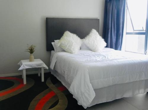 a bedroom with a white bed with two pillows at Bounce Modern Home of Comfort 2 in Midrand