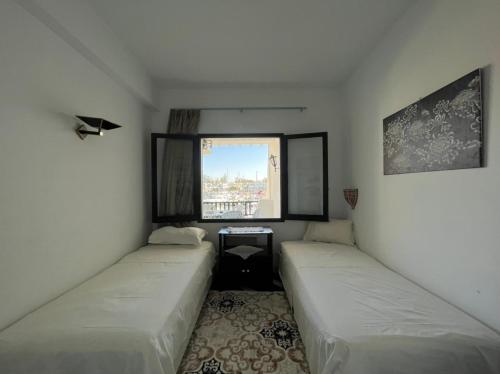 two beds in a small room with a window at Appartement maria marina in Sousse