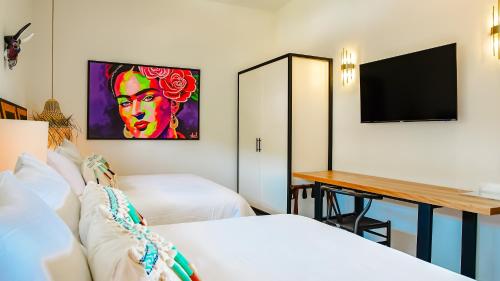 a hotel room with two beds and a desk at La Puesta Sayulita in Sayulita