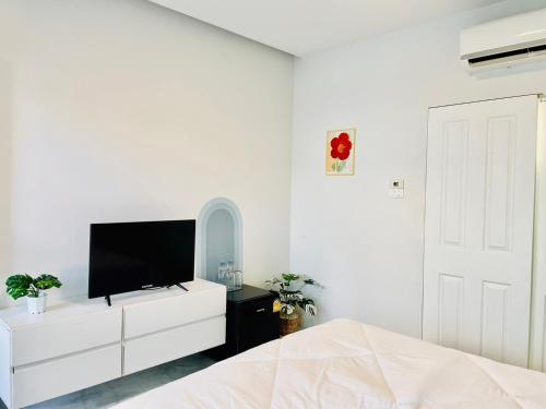 a white bedroom with a tv and a white dresser at Sky View Home and Hostel Chiangmai in Chiang Mai