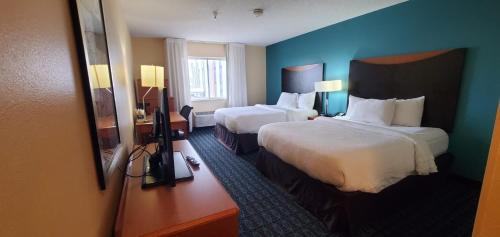 Habitación de hotel con 2 camas y paredes azules en Quail Springs Inn & Suites, en Oklahoma City