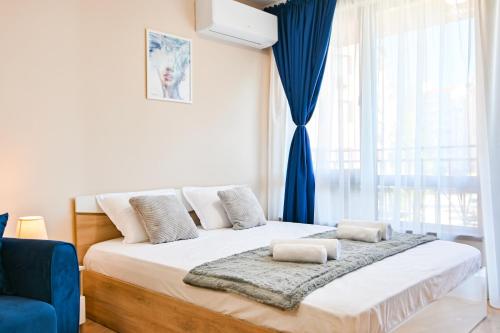 een slaapkamer met een groot bed en een blauw gordijn bij Armand de Azurro in Sofia