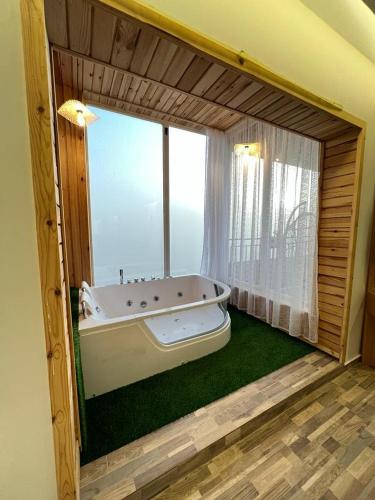 una grande vasca da bagno in una stanza con finestra di فندق كوخ الضباب النماص a Al Namas