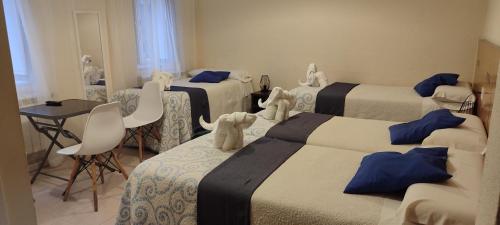 a hotel room with three beds with stuffed animals on them at Pensión Mar in Portomarin